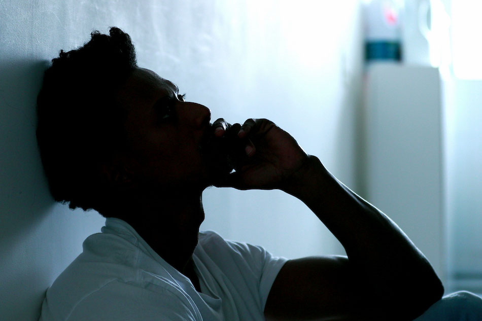 Man sitting against wall showing dejected posture