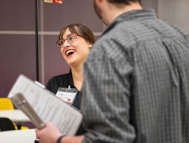 student laughing with employer holding resume