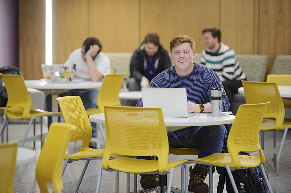 student sitting at a table in the commons